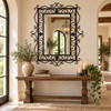 Rectangular ornate wrought iron mirror with scrollwork frame in a refined entryway