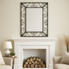 Rectangular iron mirror frame with a scrollwork design in a leving room hanged above a fireplace as the room focal point