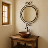 Wrought iron round mirror with scroll finials in a bathroom in a rustic modern style
