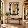 Ornamental wrought iron mirror with scrollwork and rope-like border in a Mediterranean hallway
