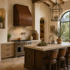 Under-cabinet hammered copper range hood with curved front in Mediterranean kitchen with stone island