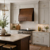 Hammered copper range hood with curved front under cabinet in transitional kitchen with island and neutral cabinetry