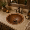 Hacienda mexican round copper bathroom sink installed in a house bathroom where its warm patina enhances rustic natural materials