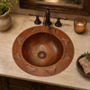 Mexican copper bathroom sink grape design installed in a house bathroom where its grape relief enhances rustic warm decor