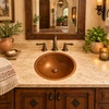 Carved round copper bathroom sink with a flower design in a warm hacienda-style bathroom