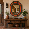 Decorative octagonal tin mirror with terracotta talavera tile accents above rustic console table