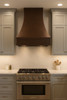 Copper bell range hood in a transitional kitchen with Shaker cabinetry, quartzite, and mixed-metal hardware