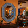 Octagonal tin mirror with blue talavera tile frame in a Mexican restaurant interior setting