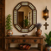 Octagonal decorative tin mirror frame with talavera tile pattern above Mexican console table