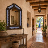Handcrafted arch tin mirror with blue pinwheel tiles decorating an adobe style hallway