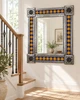 Mexican sun tile mirror on a bright staircase landing with wood stairs and warm plaster walls