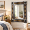 Mexican Talavera sun mirror above a dresser in a bright guest bedroom with warm wood and neutral textiles