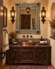 Mexican tin mirror in Spanish Colonial powder room with plaster walls, carved wood vanity and copper sink