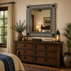 Hacienda style tin mirror with orange talavera tiles above wooden dresser in a rustic mediterranean bedroom