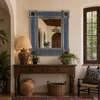 Mexican metal frame tile mirror Spanish Colonial Talavera pattern displayed above rustic console in warm interior with window and natural light
