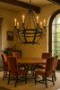 Hacienda style iron chandelier with candle lights over dining table in Spanish Revival dining room with iron accents