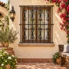 Black wrought iron window guard with scroll top design on a Spanish colonial patio wall