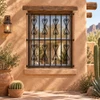Black wrought iron window guard with scroll top design on a warm desert adobe home