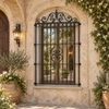 Wrought iron door guard with curved crest and heart scrolls on an old-world arched doorway