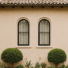 Spanish Revival iron window guard for arched windows installed on two windows of a Mission style house