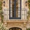 Wrought iron balcony railing with arched and twisted bars on an old-world townhouse with stone trim