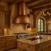 Minimalist copper range hood with round chimney in upscale rustic kitchen, hammered copper canopy above natural wood cabinetry, stone surfaces and exposed timber beams