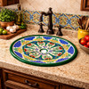 Talavera grape motif bathroom sink used in a kitchen space with rustic cabinetry and handcrafted accents
