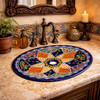 Navy orange star talavera bathroom sink in Spanish revival bathroom with arched mirror and iron lighting