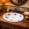 Oval blue floral talavera mexican bathroom sink featured in Mexican style restaurant restroom with rustic wood vanity