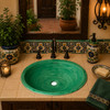 Oval ceramic Mexican sink with green scrollwork enhancing a warm Hacienda-style bathroom vanity.