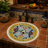 Mexican bathroom sink with colorful artisan patterns featured in a rustic kitchen bar with artisan ceramic tile countertop