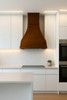 Rustic bell-shape copper range hood installed in a modern kitchen