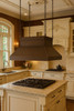 Chain suspended hammered copper island range hood in Victorian style in nineteenth century English kitchen, warm patina canopy above island cooktop with period inspired furnishings
