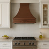 36 inch Old European copper range hood with decorative scroll motif in transitional kitchen, hammered copper canopy with warm patina above balanced cabinetry and stone surfaces