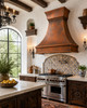 Rustic hammered copper range hood in Spanish Colonial kitchen with white plaster, dark timber and handmade tile