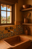 Traditional wall-mount brass faucet with Talavera tile backsplash in a colorful Spanish revival kitchen.