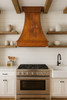 Country kitchen copper exhaust hood in farmhouse kitchen, curved copper canopy with warm rustic patina above shiplap walls and wood accents
