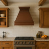 Classic copper range hood with rustic design in farmhouse kitchen, hammered copper canopy with warm patina above shiplap walls and wood accents