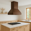 Modern pyramid copper range hood in Nordic kitchen with white walls, light oak and warm copper patina