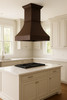 High ceiling island 36-inch copper range hood in transitional kitchen, tall hammered copper canopy with dark rustic patina above balanced cabinetry