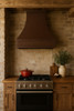 28 x 24 inch hammered under-cabinet copper stove hood in a rustic kitchen with tapered bell shape and distressed wood cabinetry