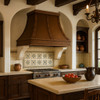 Wall mount copper range hood in Spanish Colonial kitchen, hammered canopy above range with wood beams and tile backsplash