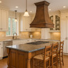 Colonial hammered copper island range hood above kitchen island, tapered bell silhouette with crown molding, hammered texture and warm copper patina finish