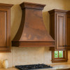 Wall mount Colonial hammered copper vent hood in traditional kitchen, tapered bell silhouette above classic cabinetry, stone backsplash and timeless architectural details