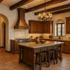 Wall mount Colonial hammered copper vent hood in Hacienda style kitchen, tapered bell silhouette above rustic cabinetry, stone surfaces and traditional architectural details
