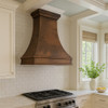 Wall mount Colonial hammered copper vent hood in Southeastern style kitchen, tapered bell silhouette above classic cabinetry, warm wood finishes
