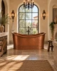 Freestanding hand hammered copper bathtub in a Spanish Colonial bathroom with plaster, Cantera stone and iron lighting