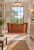 Freestanding hand hammered copper bathtub in a transitional bathroom with natural stone, simple cabinetry and metal fixtures