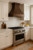Luxury copper range hood with wide apron and small crown molding in transitional kitchen, hammered copper canopy above balanced cabinetry and refined stone surfaces