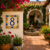 Talavera tile plaque number eight with Mexican floral border installed in a Spanish courtyard among stucco walls and greenery